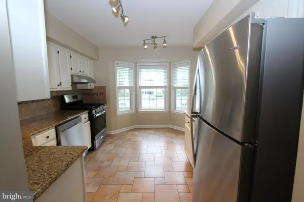 a kitchen with stainless steel appliances granite countertop a refrigerator a stove a sink and dishwasher