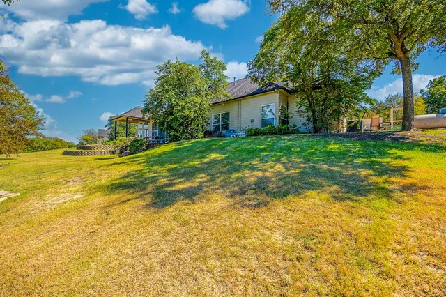 a view of a house with a big yard and large trees