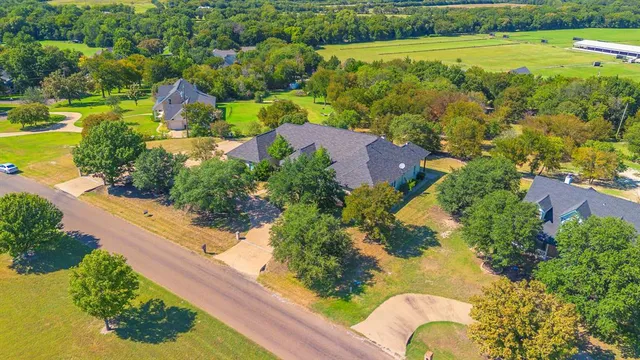 an aerial view of a residential houses with outdoor space and trees all around