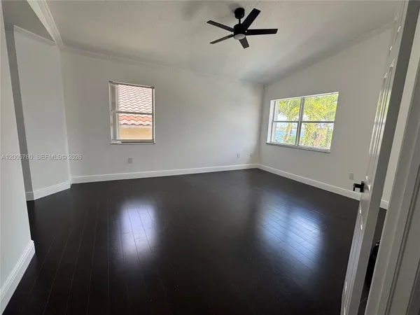 an empty room with wooden floor and windows