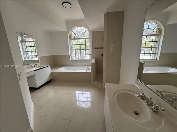a spacious bathroom with a bathtub windows and a sink
