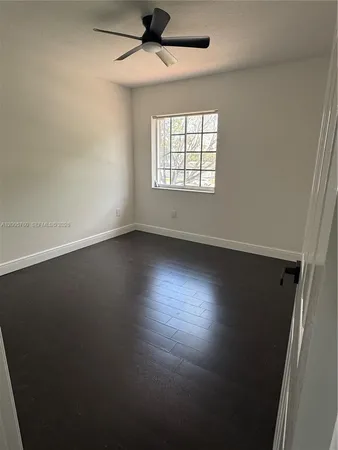 an empty room with wooden floor fan and windows