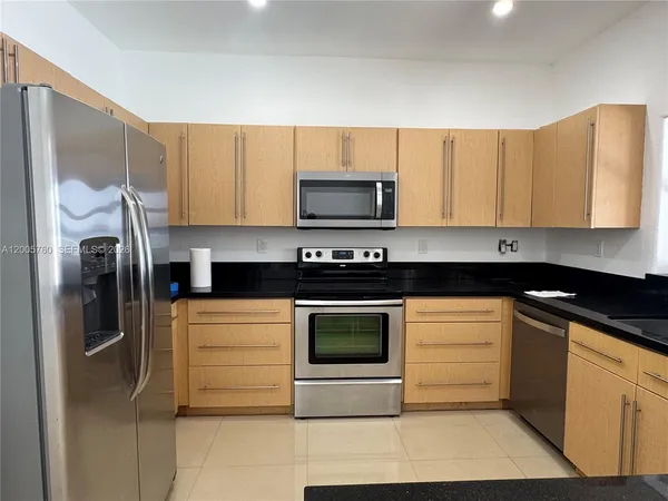 a kitchen with stainless steel appliances granite countertop a stove a microwave and a refrigerator