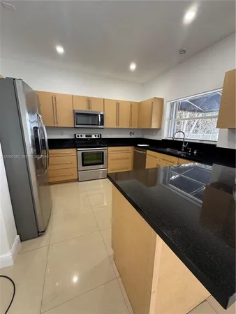 a kitchen with stainless steel appliances a sink a stove top oven a refrigerator and cabinets