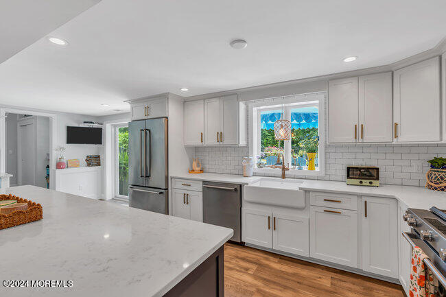 3235 Ridgewood Road Allenwood, NJ 08720 - Photo 28 of 53 a kitchen with stainless steel appliances a stove a sink dishwasher a refrigerator and white cabinets with wooden floor