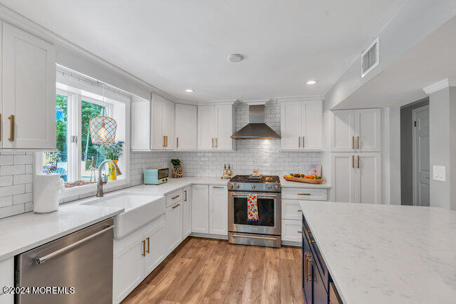 3235 Ridgewood Road Allenwood, NJ 08720 - Photo 30 of 53 a kitchen with stainless steel appliances granite countertop a stove a sink dishwasher a refrigerator white cabinets and wooden floor