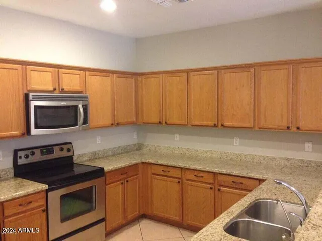 a kitchen with granite countertop a sink dishwasher stove and microwave with wooden cabinets