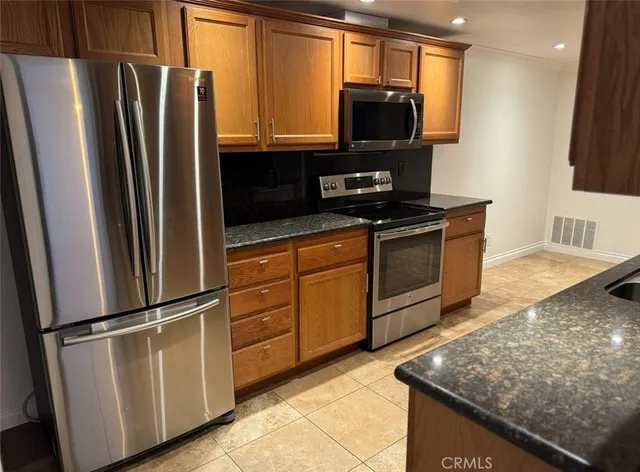 a kitchen with granite countertop a refrigerator stove and microwave