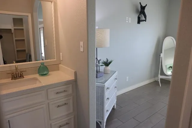 a en suite bathroom with a granite countertop sink and a mirror