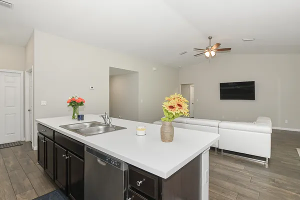 a kitchen that has a sink and a stove with wooden floor