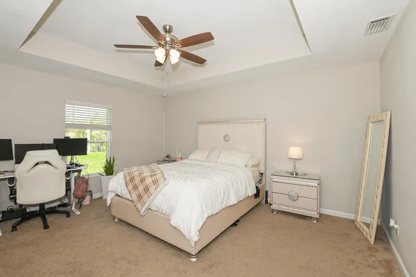 a bedroom with a bed a couch and a ceiling fan