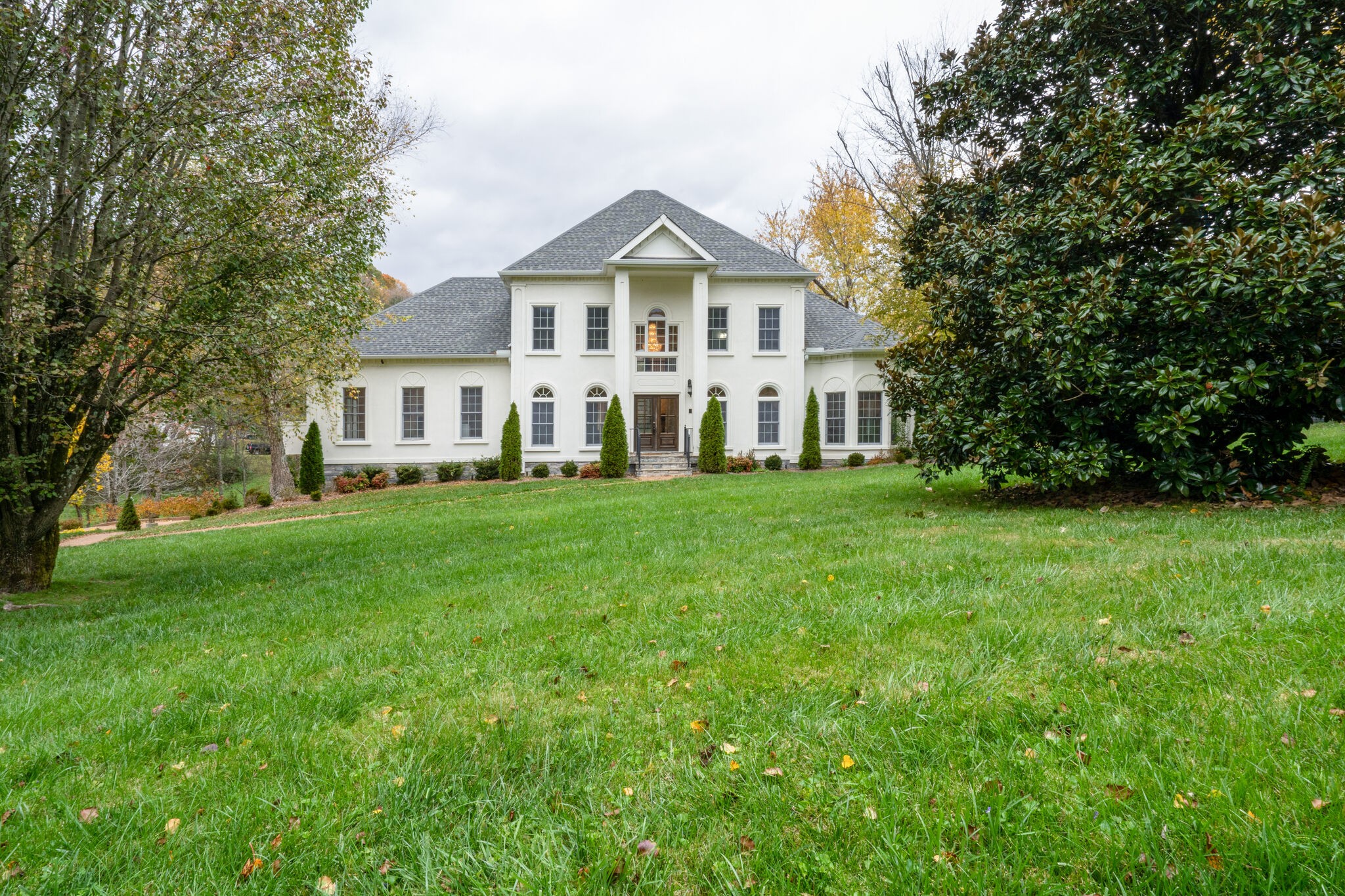 a view of a house with a big yard and large trees