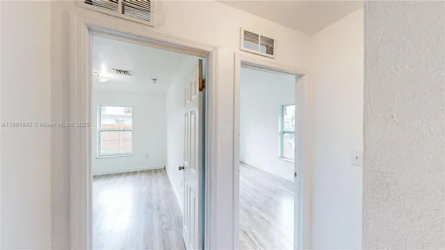 a view of empty room with wooden floor and fan