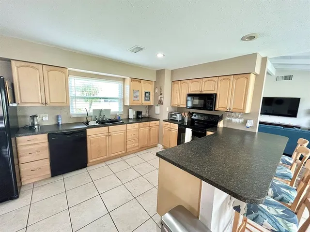 a large kitchen with granite countertop a stove a sink a counter space and dining table