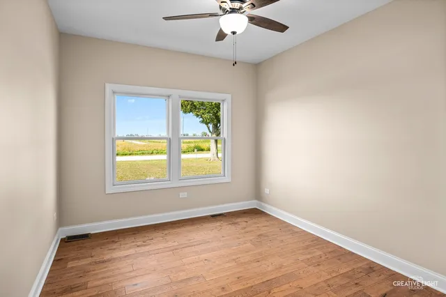 an empty room with a window and a ceiling fan