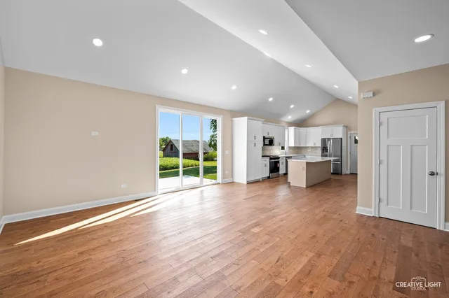 a view of empty room with wooden floor and windows