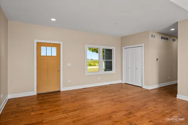 a view of an empty room with window and wooden floor