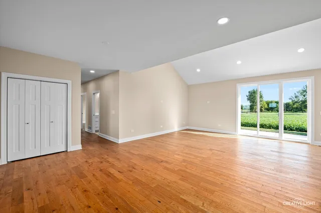 a view of an empty room with wooden floor and windows