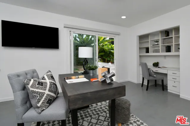a view of a white house with a large windows and lawn chairs