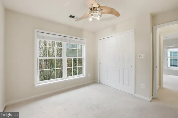 an empty room with windows and chandelier fan