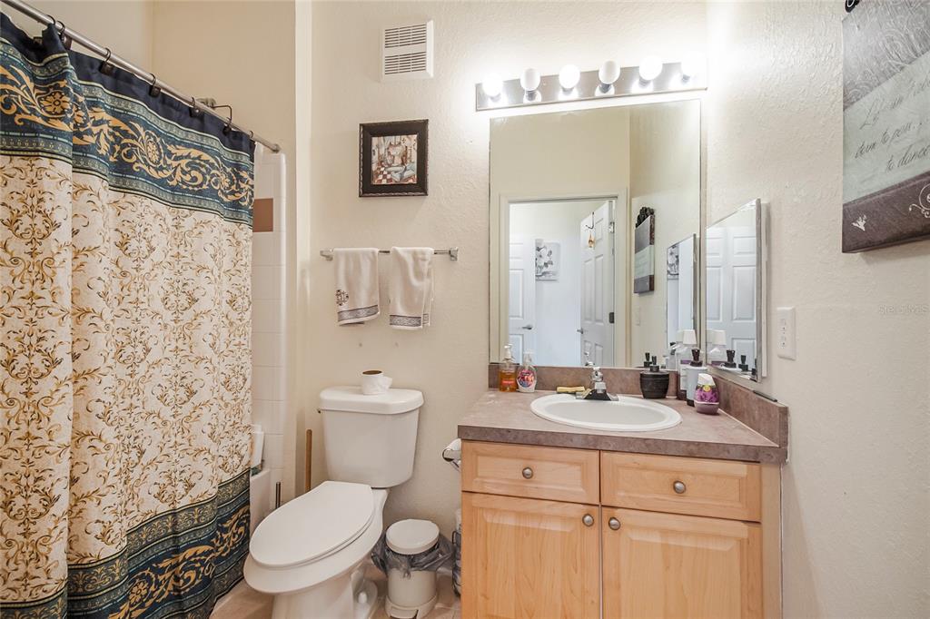 612 Terrace Ridge Circle, Unit 612 Davenport, FL 33896 - Photo 9 of 45 a bathroom with a sink a toilet a mirror and shower curtain