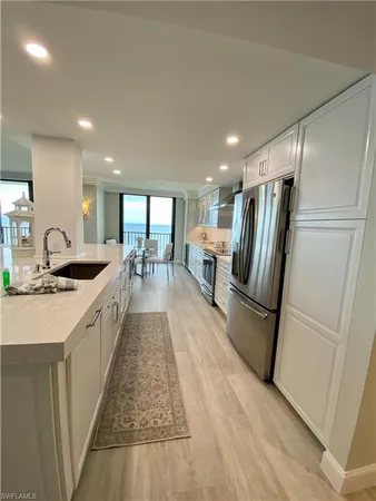a large white kitchen with a sink and refrigerator