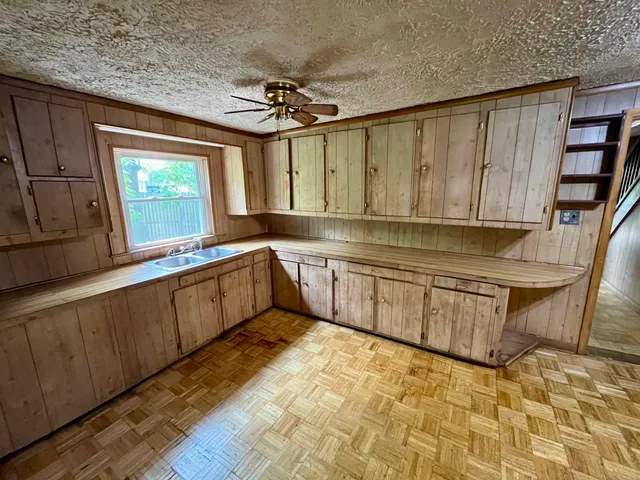 a large kitchen with granite countertop a sink cabinets and window