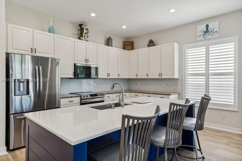 8911 Chestnut Ridge Way Boynton Beach, FL 33473 - Photo 6 of 20 a kitchen with stainless steel appliances a white table chairs and a refrigerator