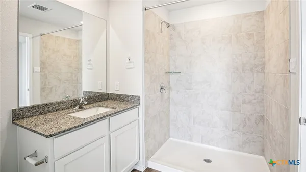 a bathroom with a granite countertop sink and a mirror a bathtub