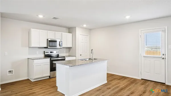 a kitchen with stainless steel appliances a sink dishwasher a stove top oven a refrigerator with wooden floors and cabinets