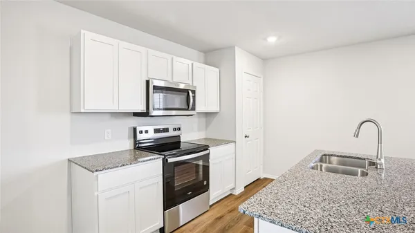 a kitchen with stainless steel appliances granite countertop a sink a stove top oven a counter space and cabinets