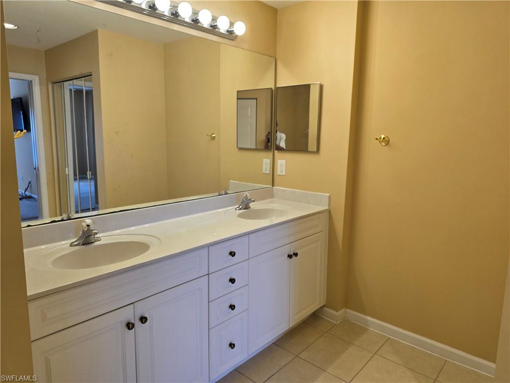 25069 Peacock Lane, Unit 101 Naples, FL 34114 - Photo 21 of 49 a bathroom with a granite countertop sink and a mirror