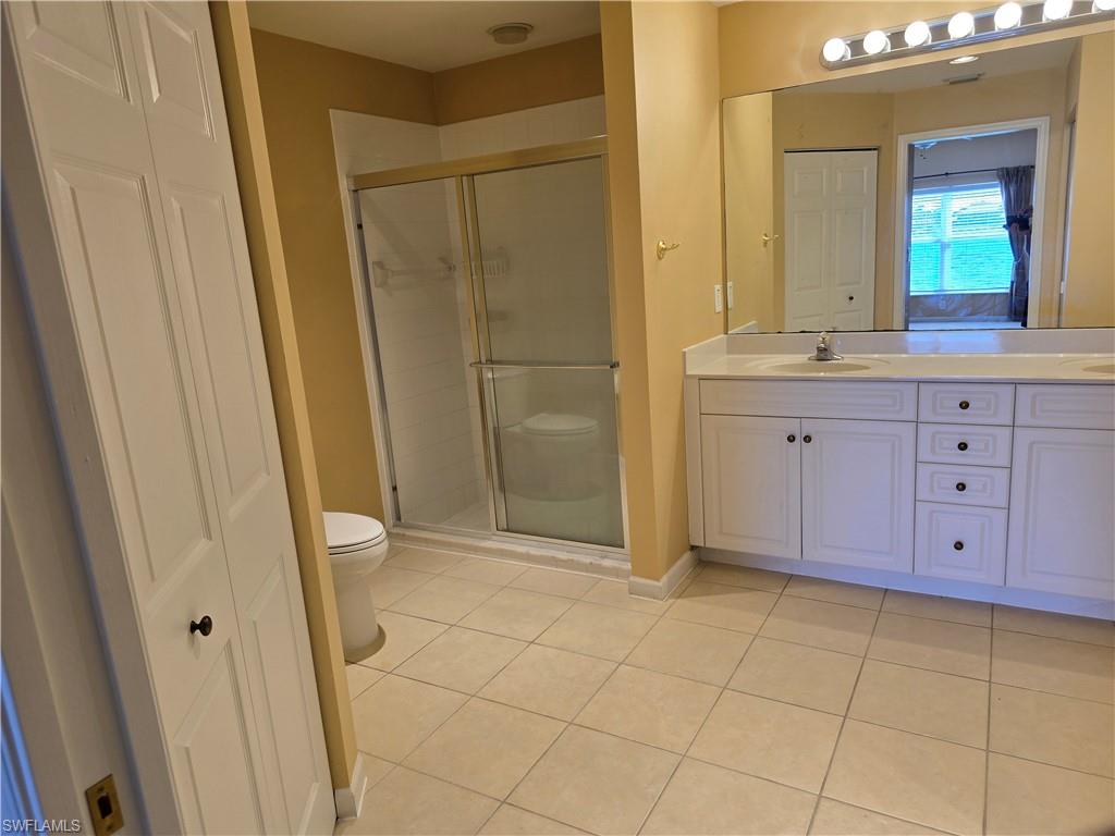 25069 Peacock Lane, Unit 101 Naples, FL 34114 - Photo 23 of 49 a bathroom with a granite countertop sink a toilet and a mirror