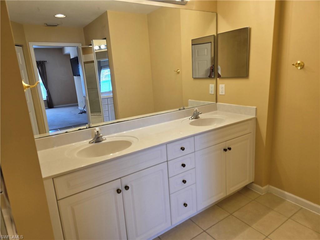 25069 Peacock Lane, Unit 101 Naples, FL 34114 - Photo 25 of 49 a bathroom with a double vanity sink and mirror