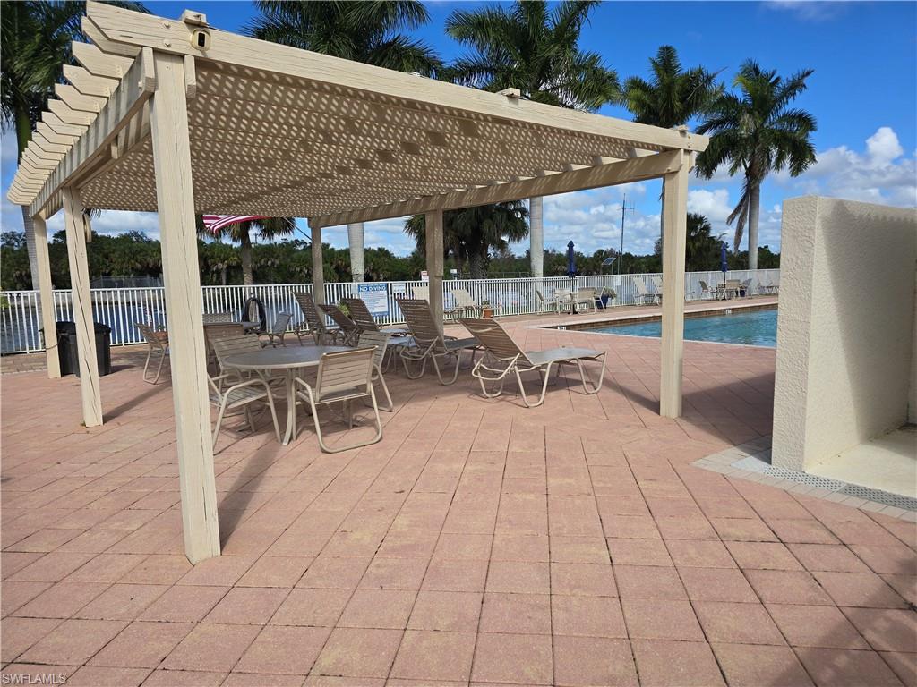 25069 Peacock Lane, Unit 101 Naples, FL 34114 - Photo 47 of 49 a view of a patio with dining table and chairs under an umbrellas