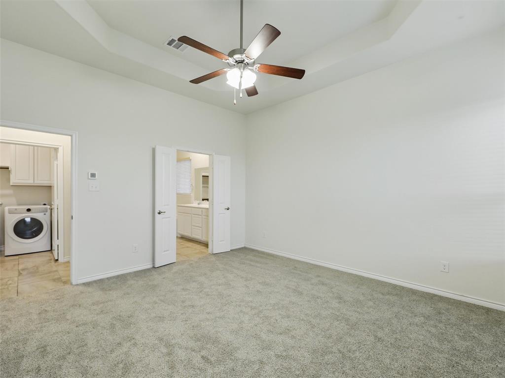 421 Maverick Street Anna, TX 75409 - Photo 14 of 25 Unfurnished bedroom featuring washer / clothes dryer, light carpet, ensuite bath, a tray ceiling, and a ceiling fan