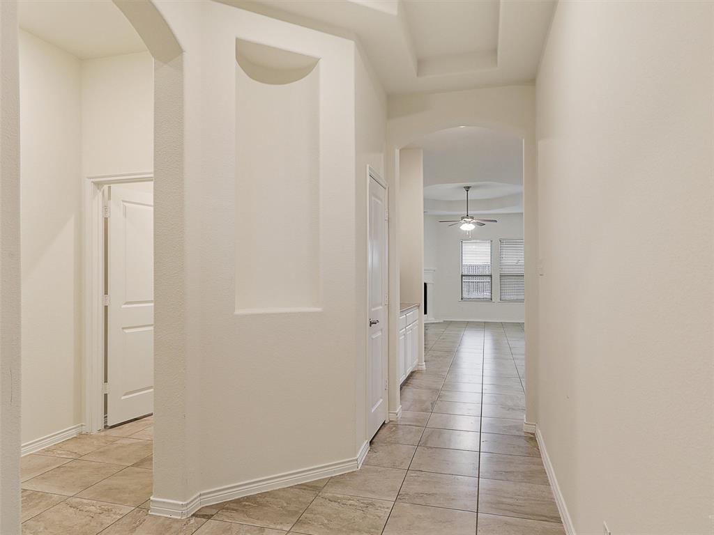 421 Maverick Street Anna, TX 75409 - Photo 5 of 25 Hallway with arched walkways, light tile patterned floors, and a tray ceiling