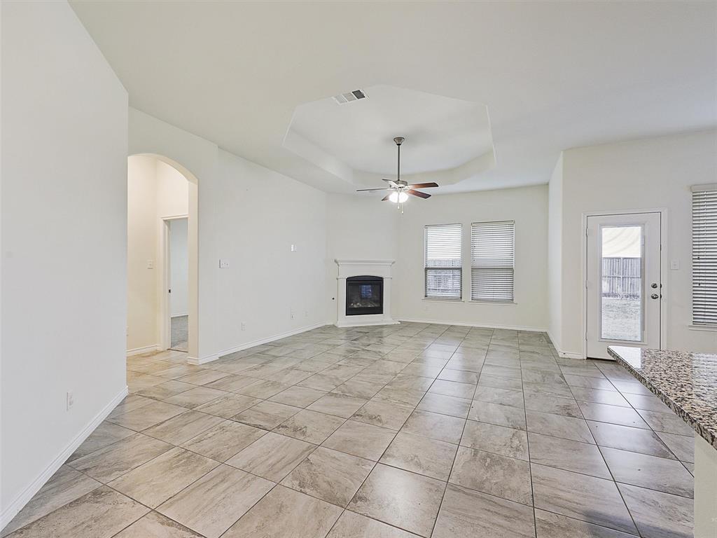 421 Maverick Street Anna, TX 75409 - Photo 10 of 25 Unfurnished living room with a ceiling fan, a raised ceiling, arched walkways, and a glass covered fireplace