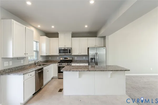 a kitchen with granite countertop a sink stainless steel appliances and white cabinets