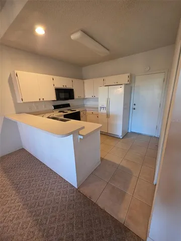 a kitchen with a sink a stove top oven a refrigerator and a window