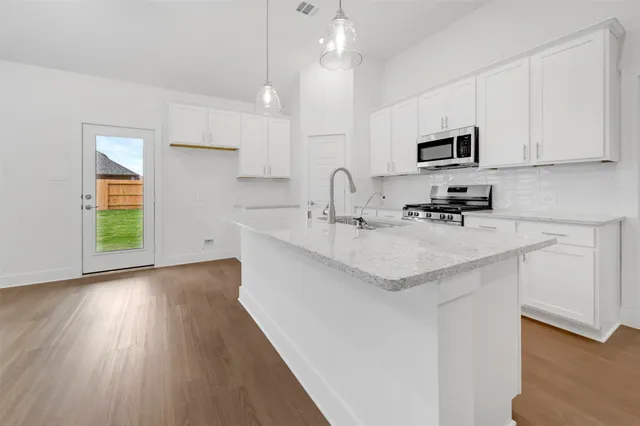 a kitchen with stainless steel appliances granite countertop a sink a stove and a wooden floors
