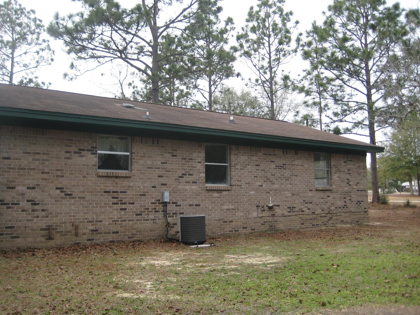 6003 Robin Road Crestview, FL 32539 - Photo 14 of 17 a brick house next to a yard with large trees