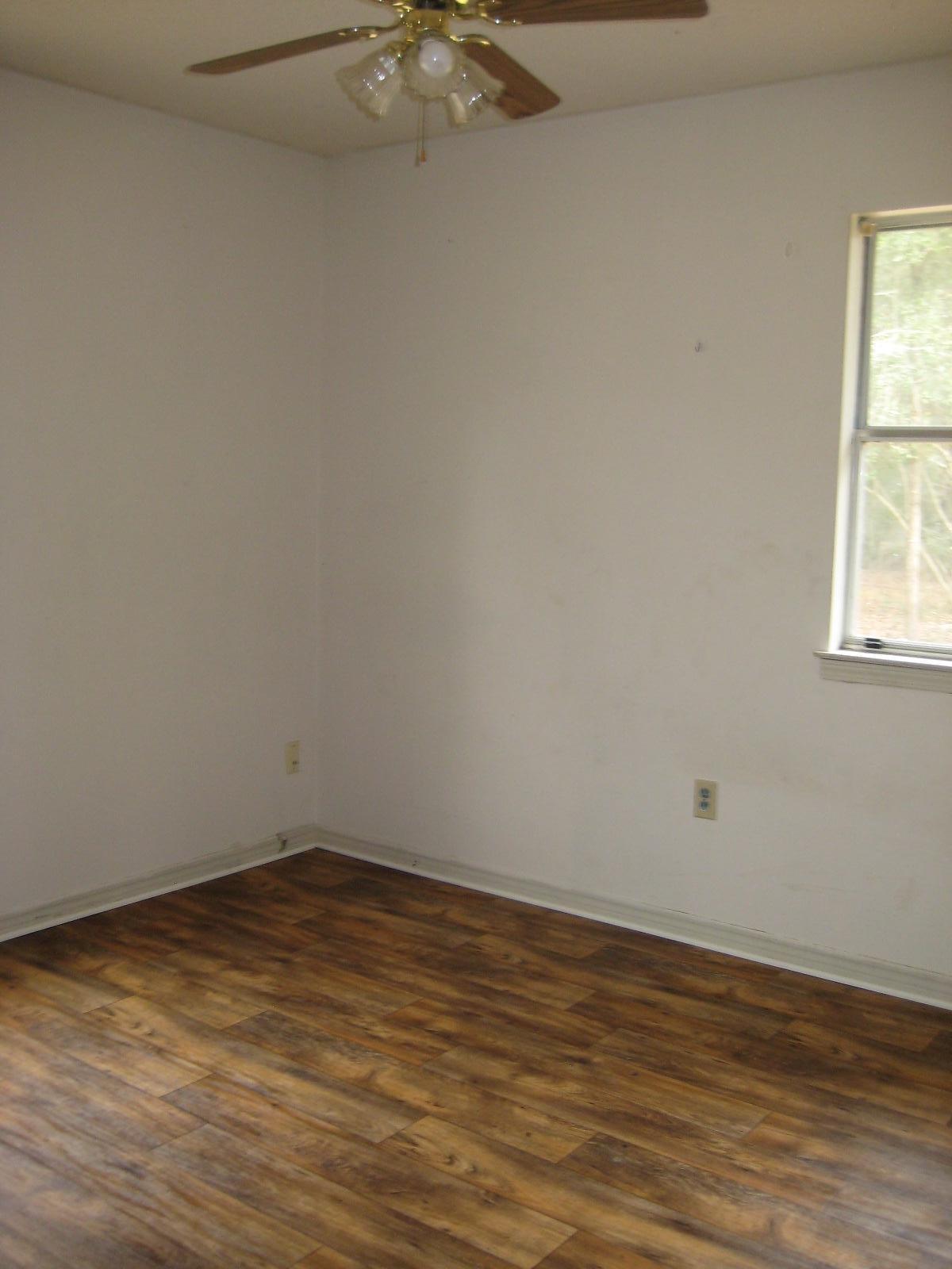 6003 Robin Road Crestview, FL 32539 - Photo 8 of 17 a view of an empty room with wooden floor and a window