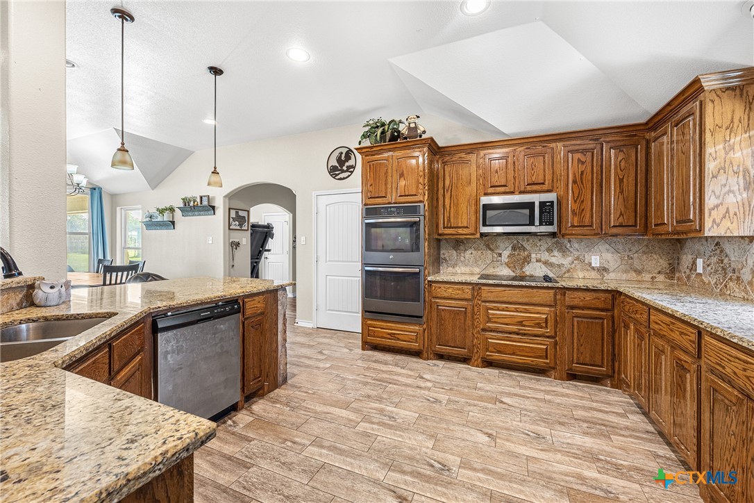 16101 Dove Road Moody, TX 76557 - Photo 9 of 42 a kitchen with stainless steel appliances kitchen island granite countertop a sink a stove and a wooden floors