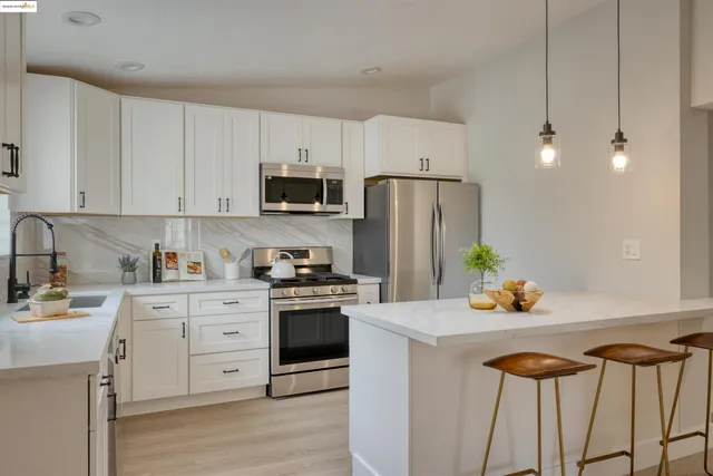 a kitchen with stainless steel appliances a stove a sink a refrigerator and cabinets