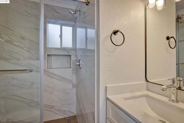 a bathroom with a granite countertop sink a mirror and shower