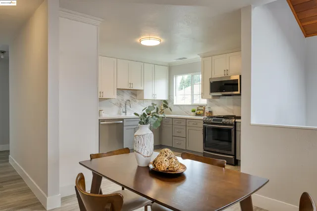 a kitchen that has stainless steel appliances a table and chairs in it