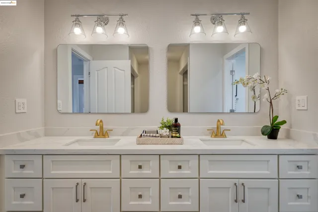a bathroom with double vanity sinks a vanity and a light fixture