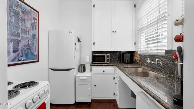 a kitchen with granite countertop a sink and a stove top oven