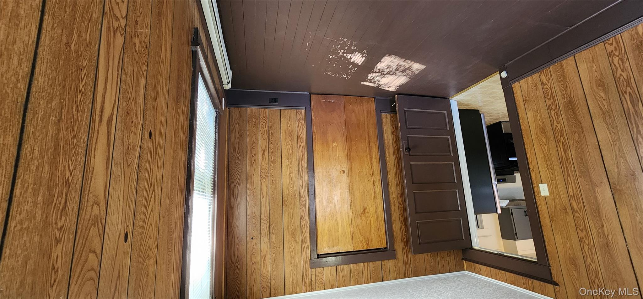 20 Delaware Street, Unit 1 Port Jervis, NY 12771 - Photo 12 of 12 Unfurnished bedroom featuring wooden walls, crown molding, dark wood finished floors, a baseboard radiator, and refrigerator